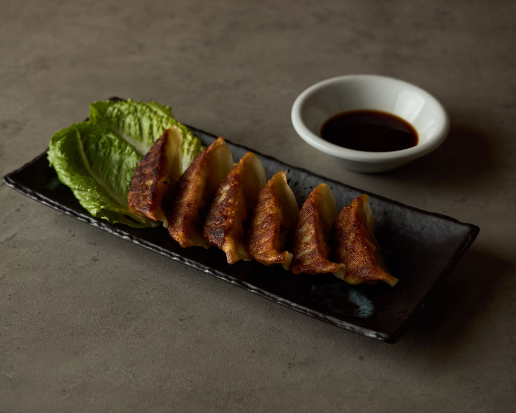 Pan-fried pork gyoza dumplings with crispy bottoms and ponzu sauce